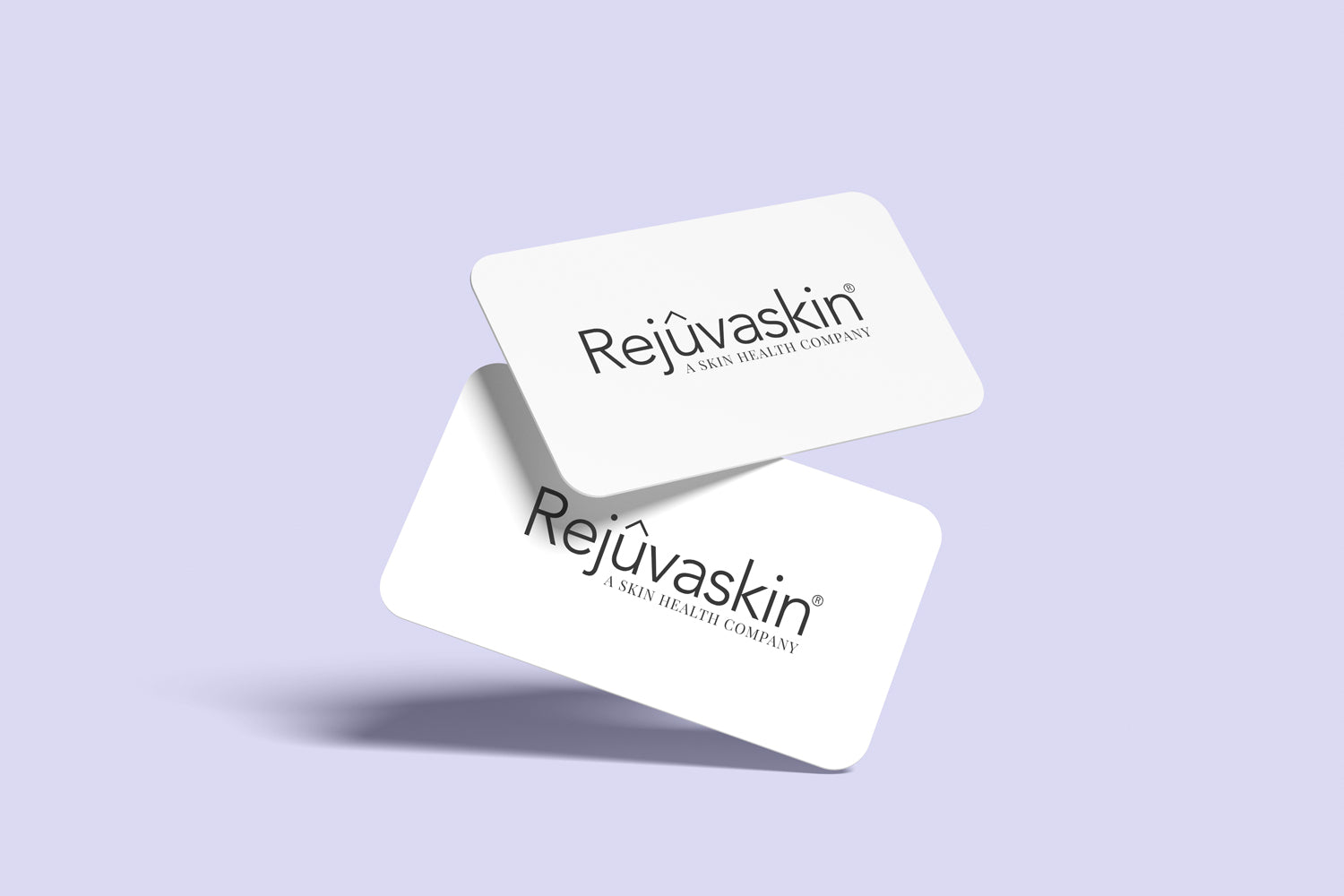 Two white gift cards with the Rejûvaskin brand logo printed on them, placed against a purple background.