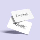 Two white gift cards with the Rejûvaskin brand logo printed on them, placed against a purple background.